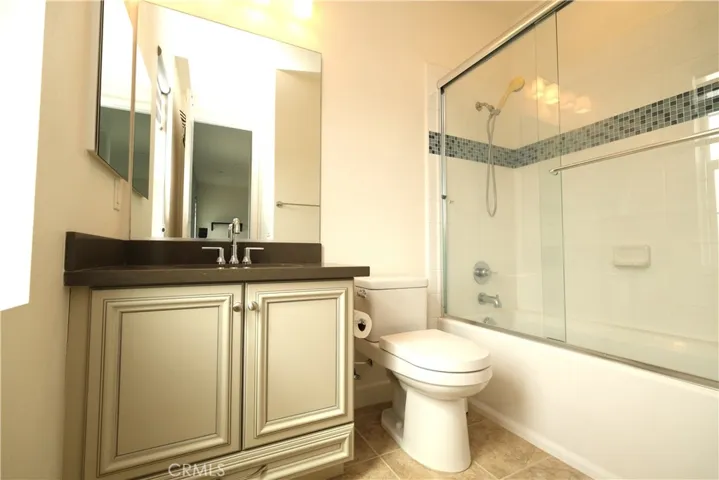 Bathroom featuring vanity storage, a glass enclosure, and tiled bathing-area walls.