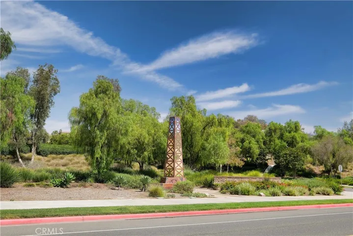 Landscaped streetscape featuring mature trees, lush planting, and decorative stone accents.