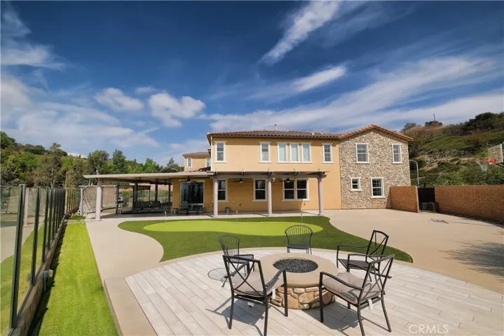 Expansive backyard featuring a fire-pit gathering area, putting green, and generous patio space.