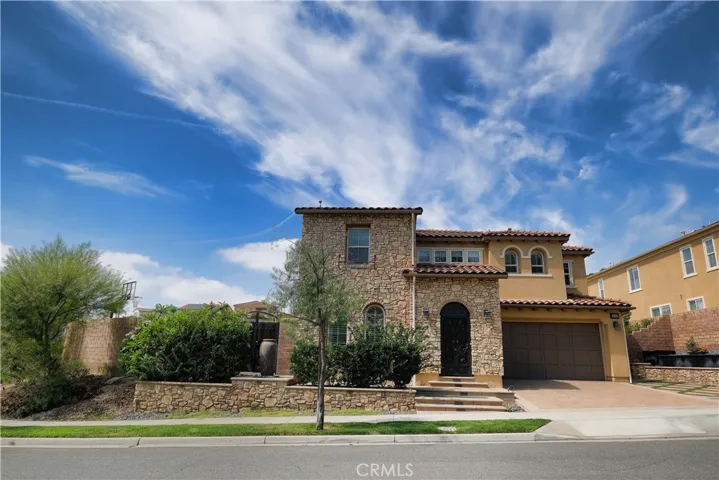 Full front view showcasing the home's two story design, arched entry, and landscaped frontage.