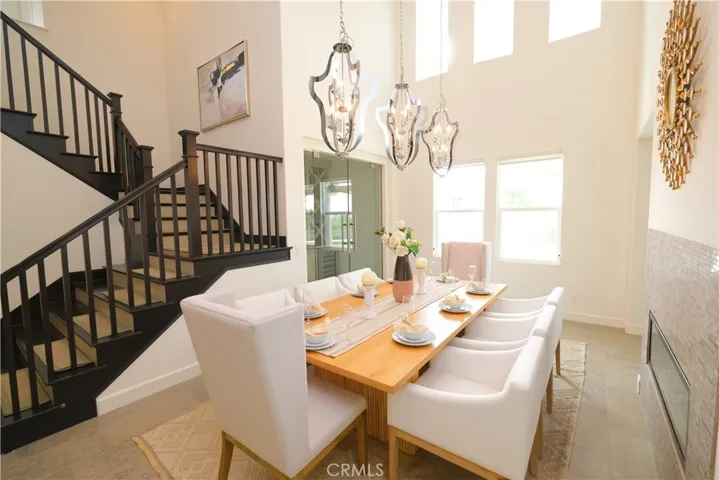 Sunlit dining room framed by the staircase and impressive ceiling height.