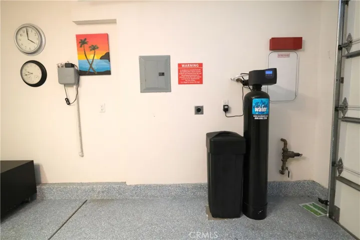 Another view of the garage, currently arranged with exercise, recreational equipment and water softener.