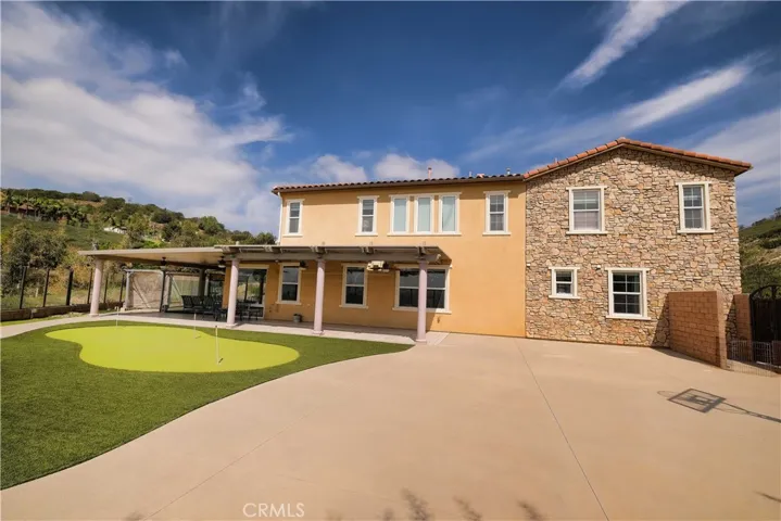 rear exterior showcasing the home's two-story design and extensive paved patio.