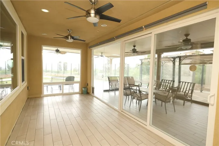 Enclosed patio featuring expansive glass panels, ceiling fans, and abundant natural light.