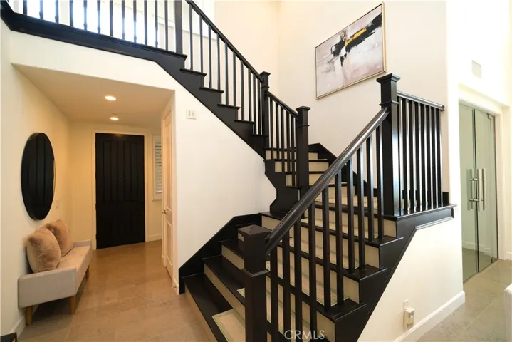 Stiking staircase with dark wood railings overlooking the open foyer.