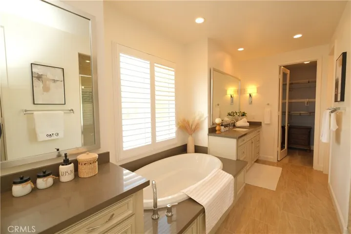 Light-filled bathroom with a bathtub, separate vanity areas, and recessed lighting.