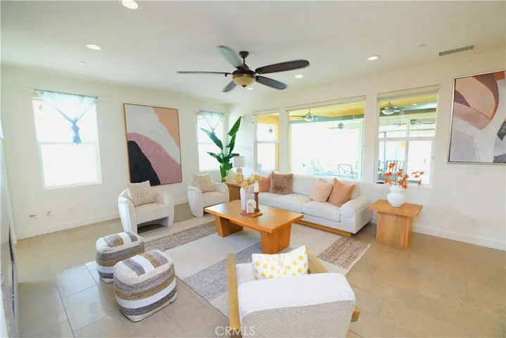 Bright family room with generous windows, a ceiling fan, and space to gather and relax.