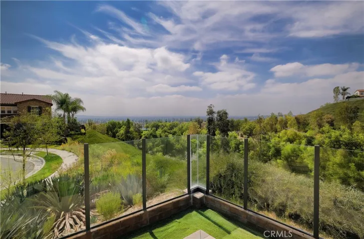 Glass-panel fencing allows views of the surrounding greenery and rolling hills.