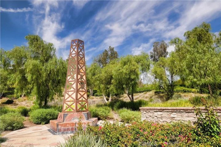 Decorative stone monument surrounded by layers landscaping and mature trees.