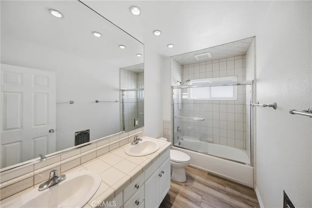 Primary bathroom featuring double sink and shower in tub.