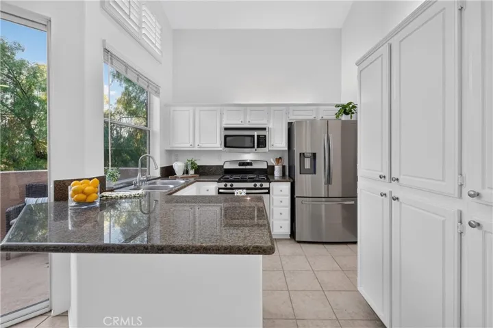 White wood cabinetry, stainless steal appliances and granite counter tops with lots of natural light