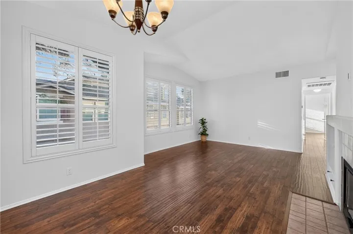 Living space with fireplace, plantation shutters, new windows, new paint and hard wood floors.