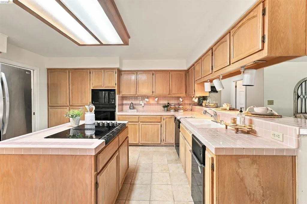 Kitchen featuring wood cabinetry, tile flooring, built-in wall oven, and a center island with an integrated cooktop