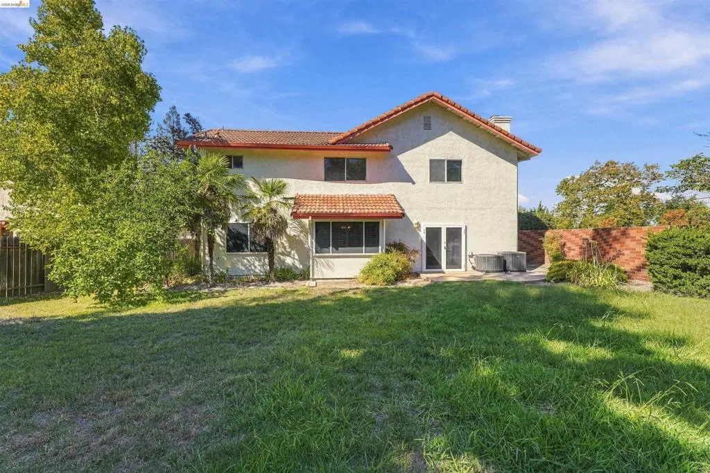 Expansive grassy yard with mature trees and a brick privacy wall