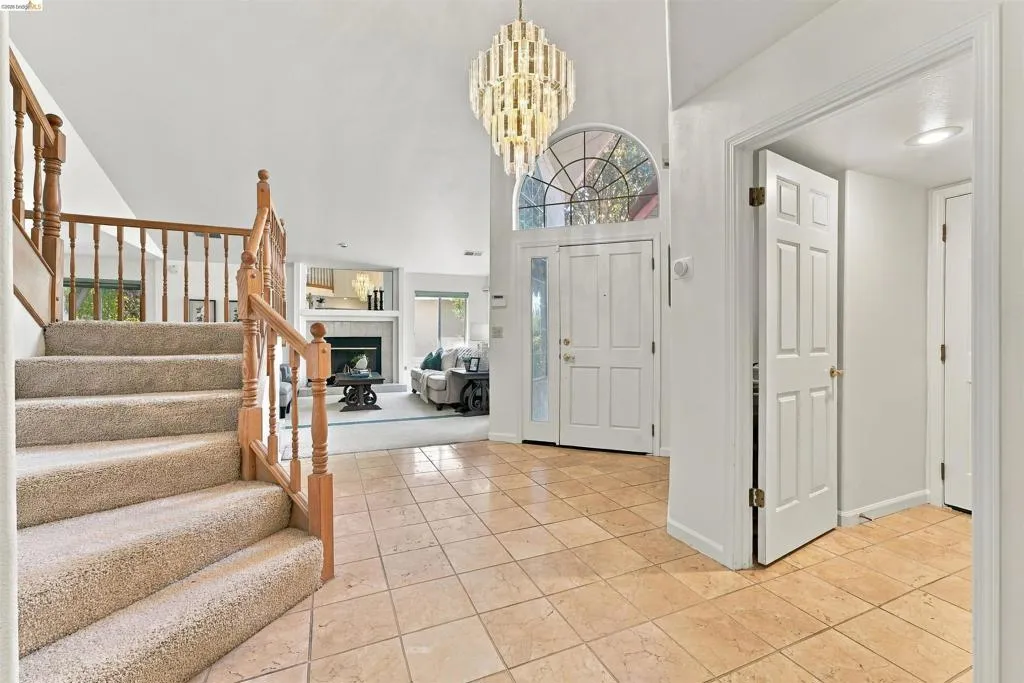 Two-story foyer with tile flooring, double entry doors with an arched transom, and a contemporary chandelier