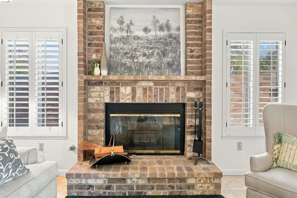 Brick fireplace with a raised hearth, black firebox, and a brick mantel
