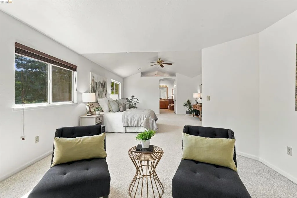 Vaulted ceiling, ceiling fan, white carpet, multiple windows with blinds, and white walls