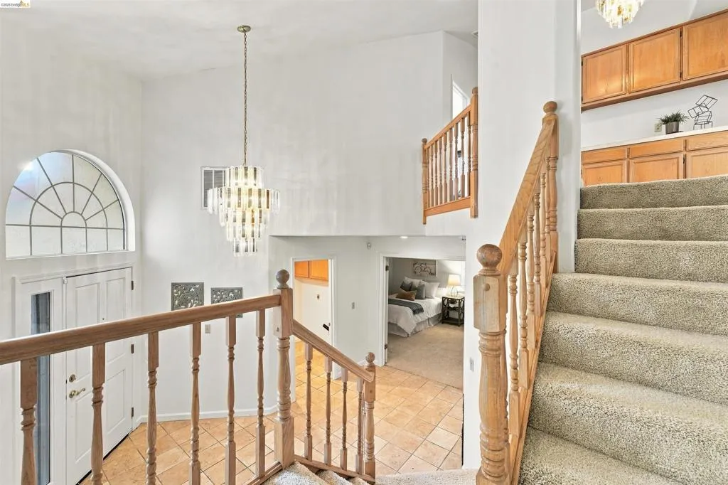 Two-story entry with an arched transom window, a multi-tiered chandelier, and tile flooring