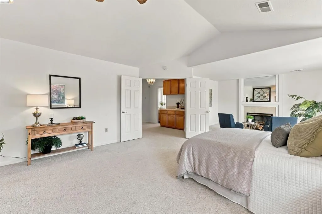 Vaulted ceiling with a fireplace, built-in shelving, and light-toned carpeting