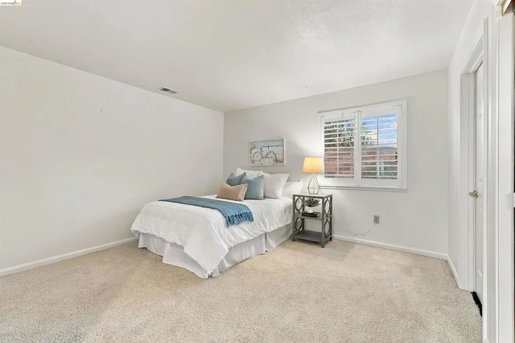 Wall-to-wall carpeting and a window with plantation shutters