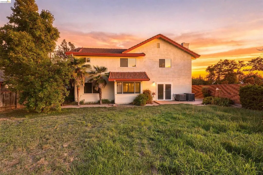 Stucco exterior with a red tile roof, featuring multiple windows, and a glass-paneled double door leading to a patio