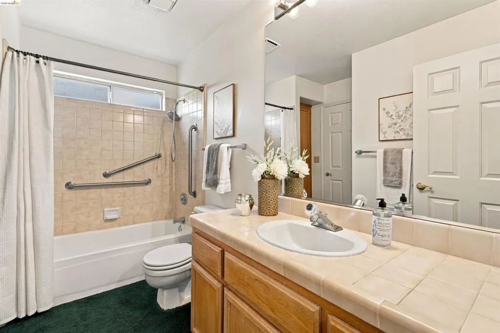 Bathroom featuring a single vanity with wood cabinetry, tile countertop, and an integrated sink