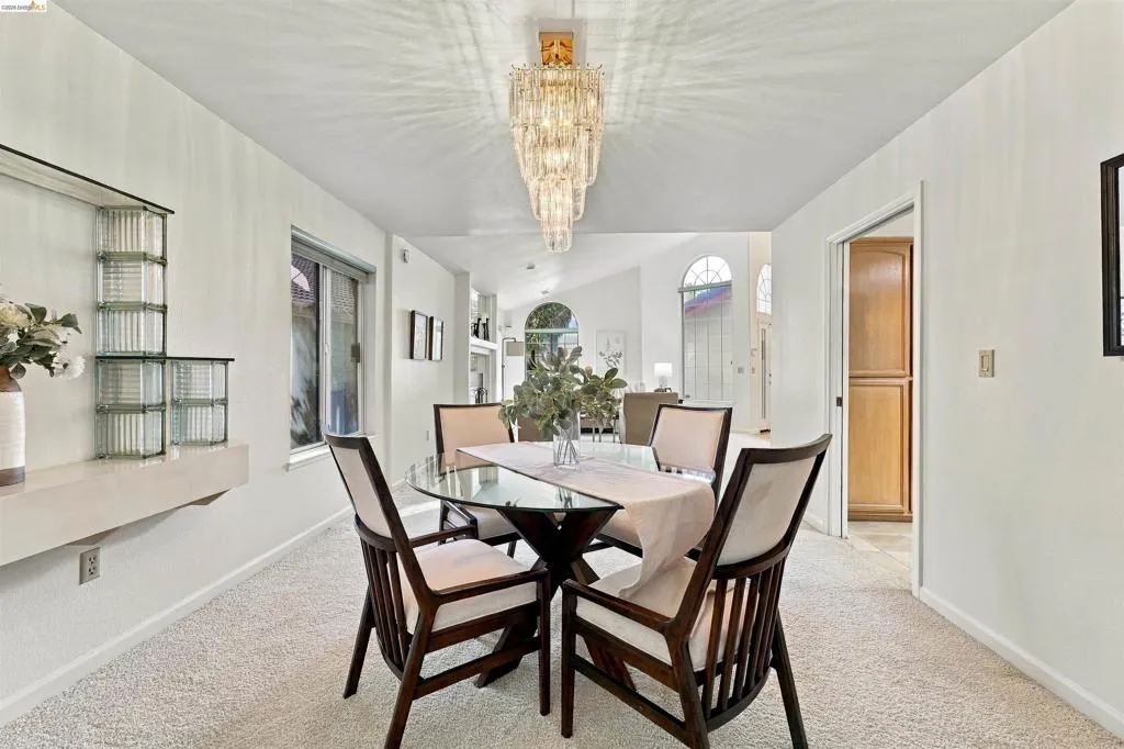 Recessed ceiling with an ornate chandelier, built-in shelving, glass block architectural accents, and white wall finishes