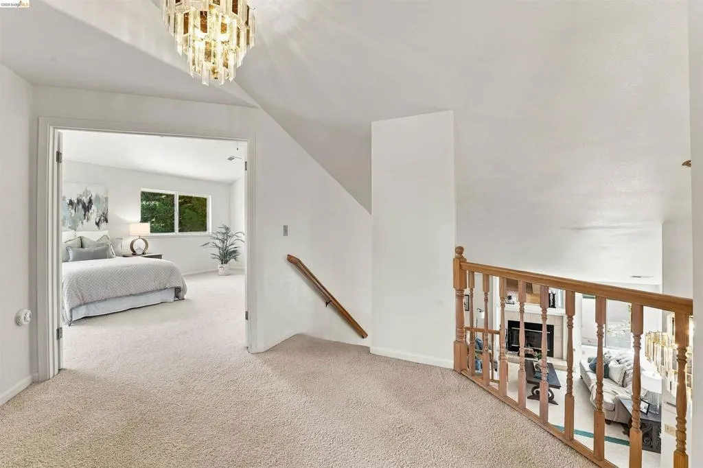 Carpeted landing with a decorative chandelier and wood railing