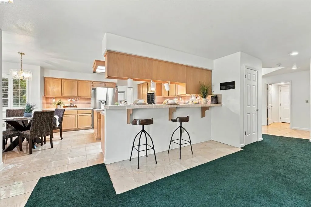 Kitchen featuring wood cabinetry, stainless steel refrigerator, and a breakfast bar with stone-look countertop