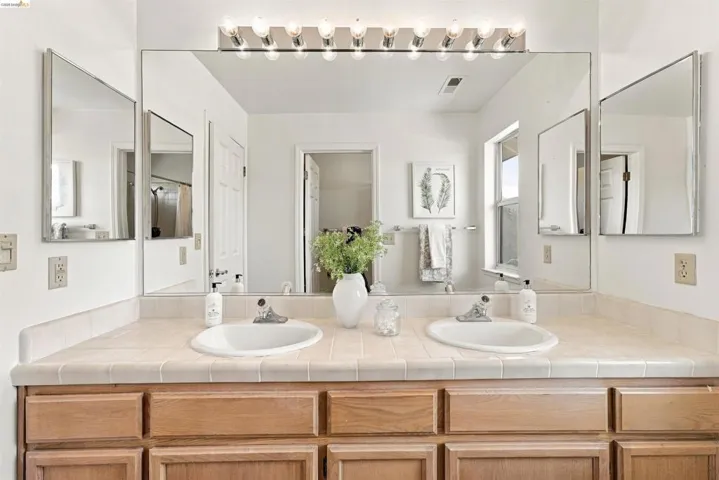 Dual vanity with ceramic tile countertop and wood-finish cabinetry