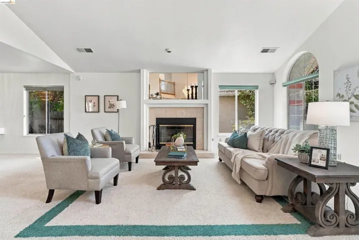 Integrated fireplace with a stone surround, arched transom window, recessed lighting, and a vaulted ceiling