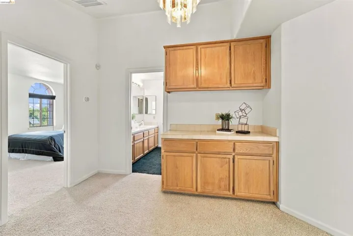Integrated cabinetry with upper and lower storage, light-toned countertop, and carpeted flooring