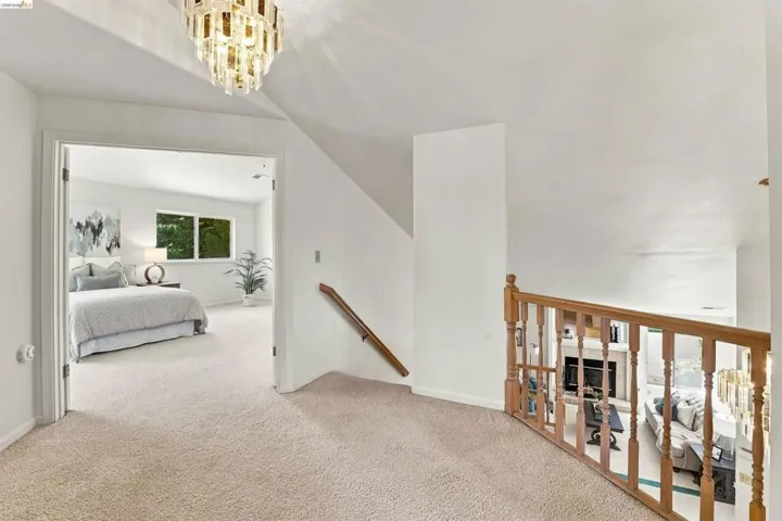 Carpeted landing with a decorative chandelier and wood railing