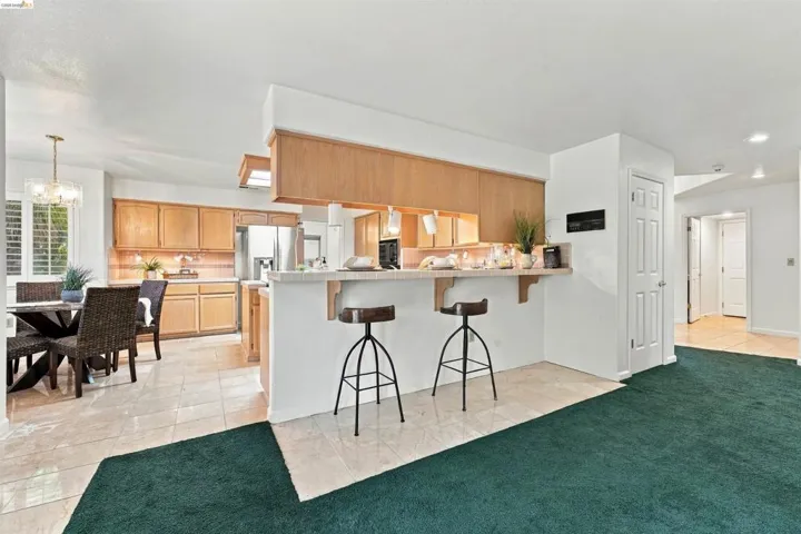 Kitchen featuring wood cabinetry, stainless steel refrigerator, and a breakfast bar with stone-look countertop