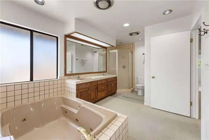 Primary bath with tub, double sinks, tiled shower & recessed lighting