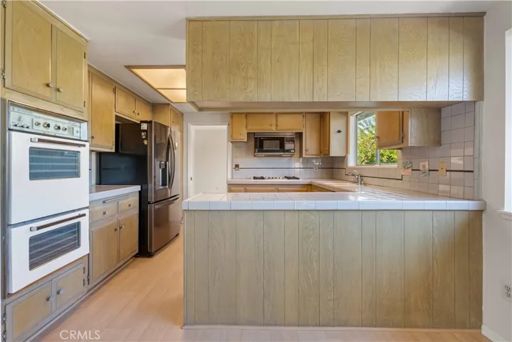 Kitchen with tile counter tops, double oven & LG fridge & dishwasher