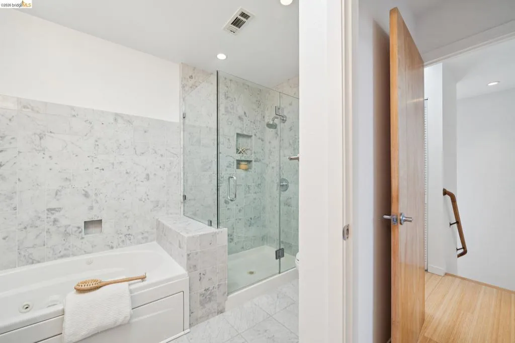 Tiled bathroom with a built-in soaking tub, glass-enclosed shower, shower niche, and recessed lighting Tiled bathroom with a built-in soaking tub, glass-enclosed shower, shower niche, and recessed lighting