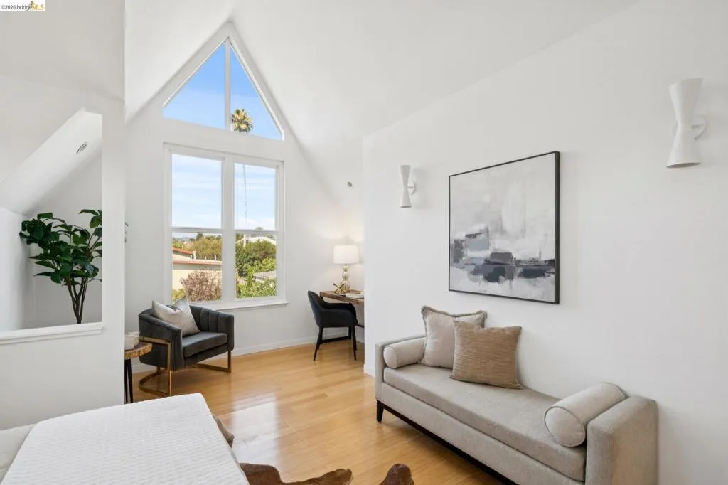 Vaulted ceiling with an architectural window, light wood-finish flooring, and wall-mounted sconces Vaulted ceiling with an architectural window, light wood-finish flooring, and wall-mounted sconces