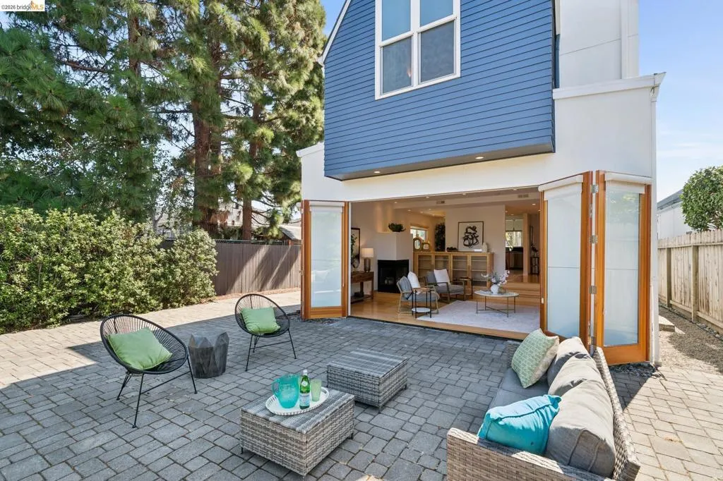 Paver patio with bi-fold doors, white exterior siding, and blue horizontal siding Paver patio with bi-fold doors, white exterior siding, and blue horizontal siding