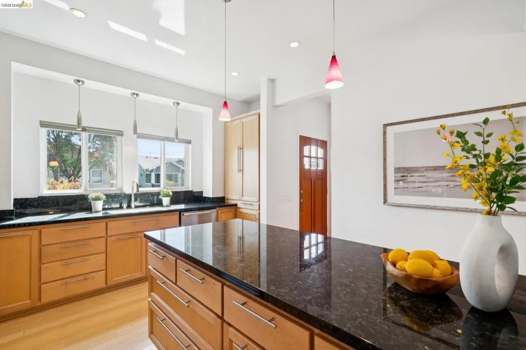 Kitchen with granite countertops, wood-finish flooring, recessed lighting, and built-in cabinetry Kitchen with granite countertops, wood-finish flooring, recessed lighting, and built-in cabinetry