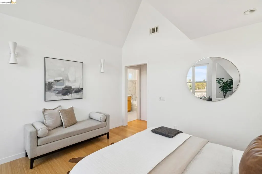Vaulted ceiling with recessed lighting, wood-finish flooring, and white wall sconces Vaulted ceiling with recessed lighting, wood-finish flooring, and white wall sconces