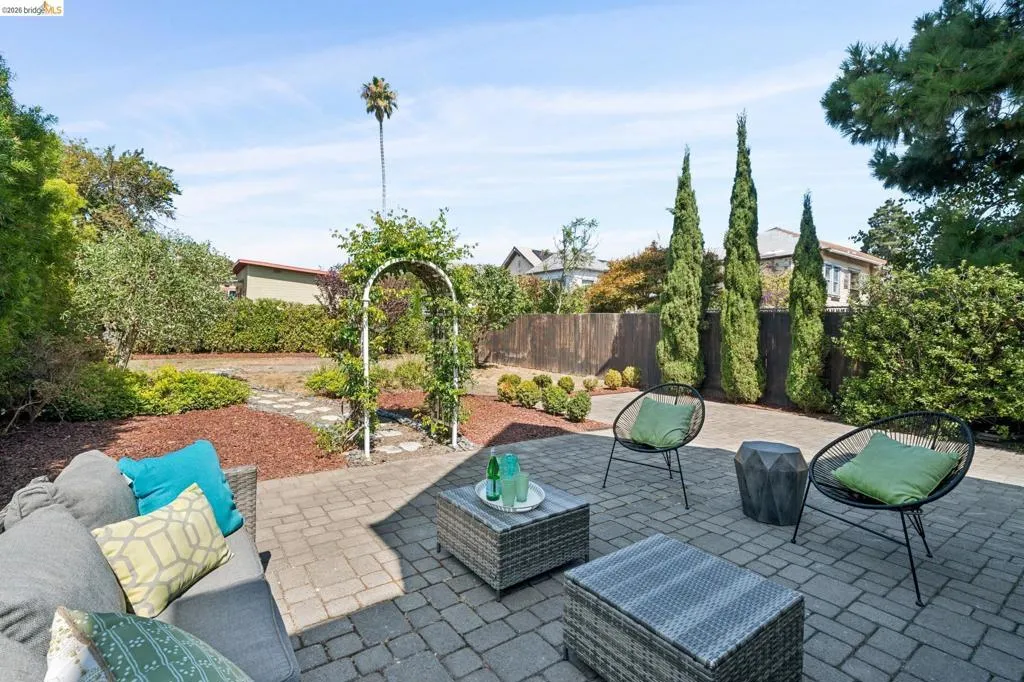 Spacious outdoor patio featuring paver stones, an archway with climbing greenery, mature landscaping, and privacy fencing Spacious outdoor patio featuring paver stones, an archway with climbing greenery, mature landscaping, and privacy fencing