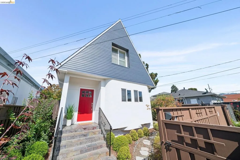 Modern A-frame architecture with a vibrant red front door, slate steps, and decorative wrought iron railings Modern A-frame architecture with a vibrant red front door, slate steps, and decorative wrought iron railings