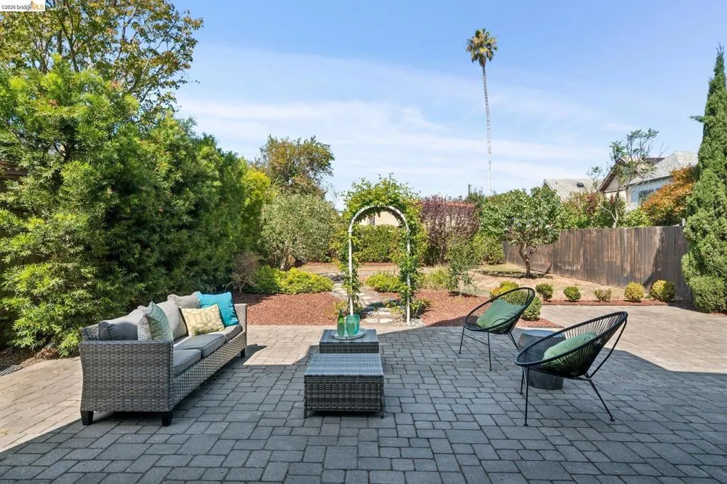Expansive paver patio with a garden archway, mature perimeter trees, and landscaping Expansive paver patio with a garden archway, mature perimeter trees, and landscaping