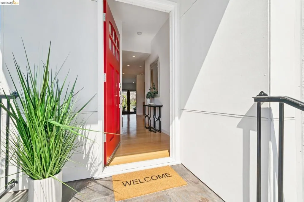 Red paneled entry door with windowpanes, stone tile entry, and light wood-finish flooring extending into the interior Red paneled entry door with windowpanes, stone tile entry, and light wood-finish flooring extending into the interior