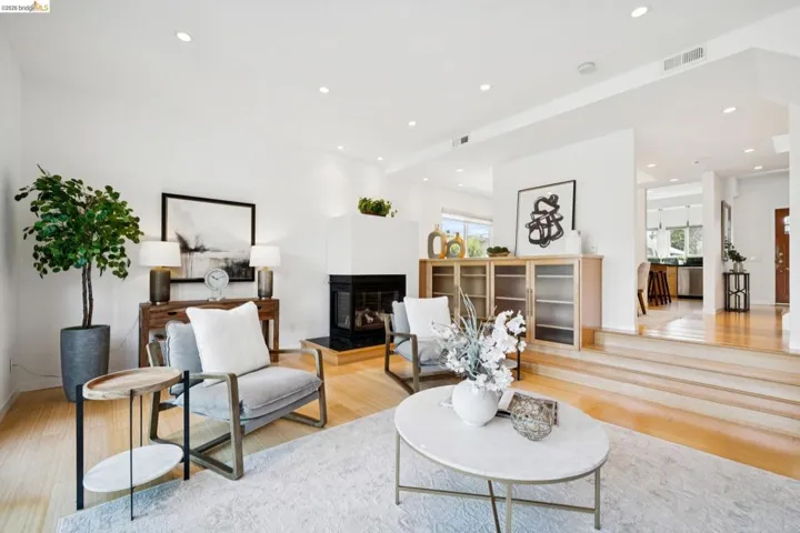 Recessed lighting illuminates the open-concept living space with light-tone wood flooring