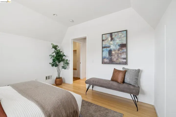 Sloped ceiling with recessed lighting, light wood-finish flooring, and white painted walls