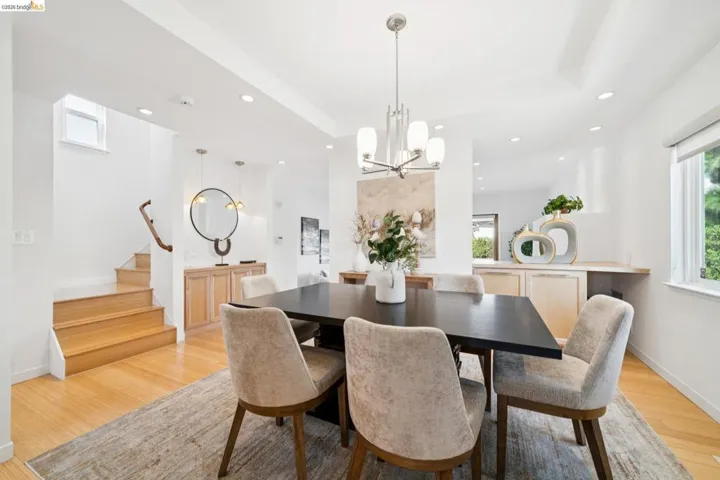 Recessed lighting, light wood-finish flooring, built-in cabinetry, and a contemporary chandelier illuminate this dining area