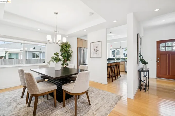 Recessed lighting, light wood-finish flooring, central chandelier, tray ceiling, and a prominent wood entry door with glass panels