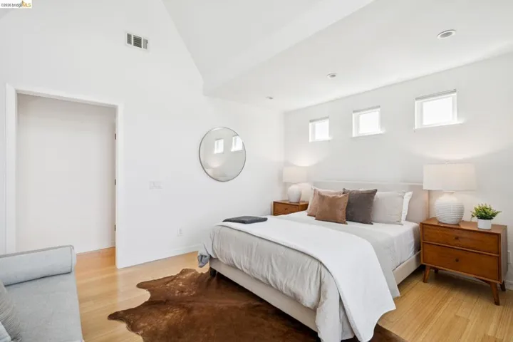 Vaulted ceiling with recessed lighting, three upper windows, and wood-finish flooring